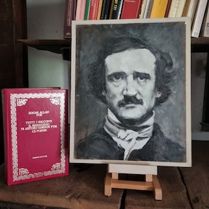 Può includere: Un ritratto in scala di grigi di Edgar Allan Poe su un piccolo cavalletto di legno. A sinistra del ritratto c'è un libro rosso con scritte dorate, intitolato "EDGAR ALLAN POE TUTTI I RACCONTI...". Librerie piene di libri sullo sfondo.
