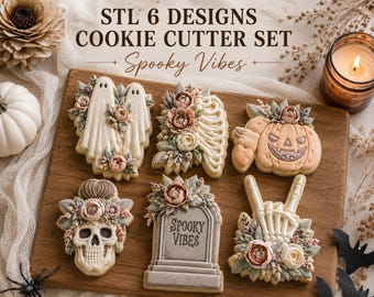 Op de afbeelding: Een set van zes koekjesvormen met ontwerpen van twee geesten, een ribbenkast, een pompoen, een schedel, een grafsteen met de tekst "SPOOKY VIBES" en een skeletthand die een rockgebaar maakt, allemaal versierd met bloemig glazuur.