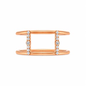 May include: A rose gold ring featuring two parallel bands connected by two vertical bars. Each vertical bar is set with a series of small, clear, round-cut stones, with a slightly larger stone positioned in the center of each bar.