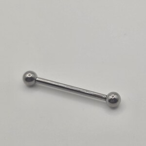 May include: A silver barbell-style body piercing jewelry. The jewelry features a straight, slender bar with a small, round ball at each end. The metal has a shiny, reflective surface.