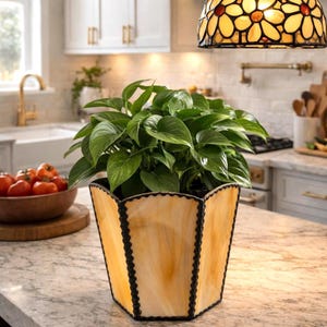 May include: A white ceramic mug with a black handle and the text "But First, Coffee" in a bold, black font. The mug is set against a blurred background, suggesting a cosy setting.