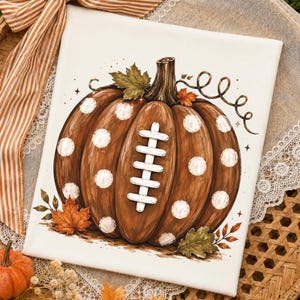Football pumpkin PNG design displayed on a white t-shirt mockup featuring a rustic pumpkin with football laces and white polka dots, perfect for football mom shirts, fall football season, game day apparel, Friday night football, autumn gifts, and football fan sublimation designs.