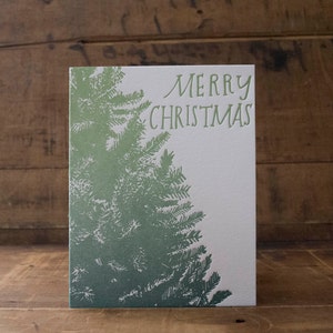 May include: A green Christmas card with a stylized image of a pine tree and the text "Merry Christmas".