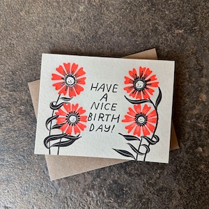 May include: A greeting card with a simple design featuring three red flowers with smiling faces. The card reads "Have a nice birth day!"