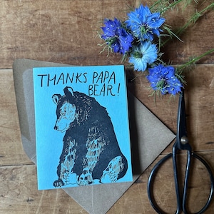 May include: A blue card with the text "Thanks Papa Bear!" and a black and white illustration of a bear sitting down.