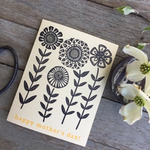 May include: A card with a black and white floral design and the text "happy mother's day!" in yellow.