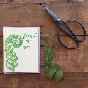 May include: A greeting card with a green fern frond illustration and the text "frond of you".