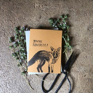 May include: A brown card with a black and white illustration of a fox and the text "You're Fantastic!" printed on it.
