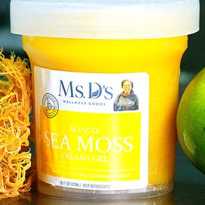 Może przedstawiać: Przezroczysty plastikowy pojemnik z kremowym żelem z alg morskich o smaku mango od Ms. D's. Pojemnik ma białą pokrywkę i żółtą etykietę z nazwą produktu i zdjęciem kobiety. Zawiera 473 ml żółtego żelu.