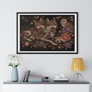 May include: Framed art print featuring two wolves with exposed rib cages, surrounded by flowers, skulls, a raven, a butterfly, and an owl. The artwork has a dark, gothic aesthetic with a black frame, perfect for adding a unique touch to any room.