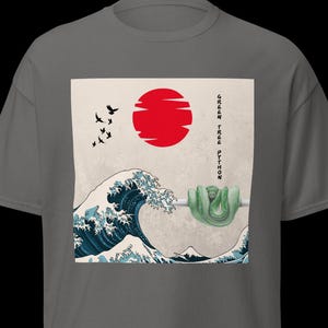May include: Grey t-shirt with a Japanese-inspired graphic. It features a red sun, a blue and white wave, and a green snake. The text "GREEN TREE PYTHON" is printed vertically. The design is reminiscent of traditional Japanese art.