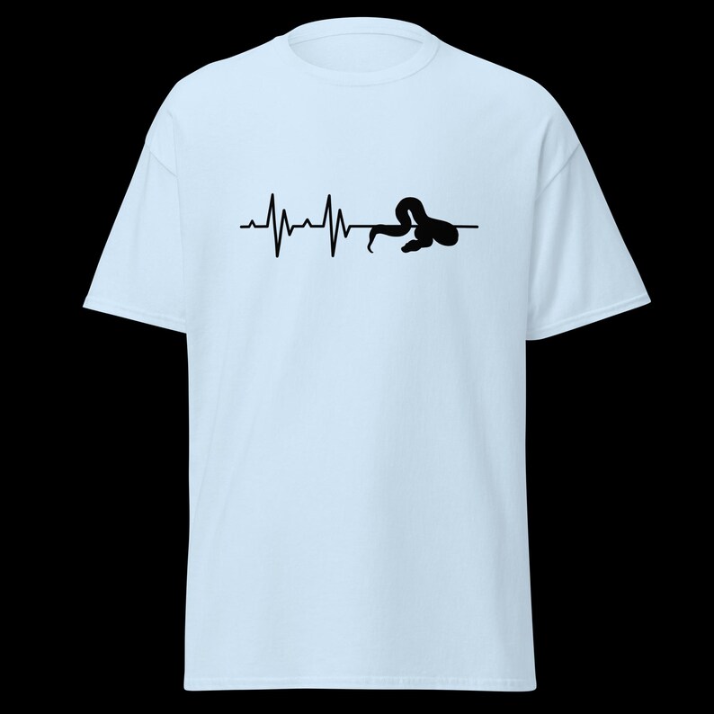 May include: Pale blue t-shirt with a black graphic. The graphic depicts a heartbeat line, ending with a curled-up snake. The design is centrally placed on the shirt.