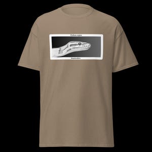 May include: A tan t-shirt with a black and white illustration of a snake's head in a white rectangular frame. The text "Python regius" and "Herpetoculture" are printed above and below the illustration.