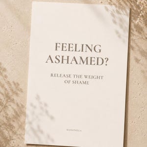 Puede incluir: Una tarjeta rectangular de color blanco hueso con texto gris oscuro que dice FEELING ASHAMED? RELEASE THE WEIGHT OF SHAME. La palabra MAISONELLA está impresa en letras pequeñas de color gris oscuro en la parte inferior central de la tarjeta, que tiene un acabado mate liso.