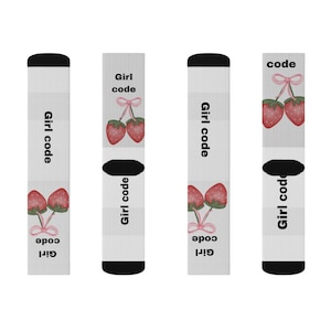May include: A pair of white socks with black cuffs and toes. The socks display the text "Girl code" and a watercolour illustration of two strawberries tied with a pink bow. The design is repeated on both socks.