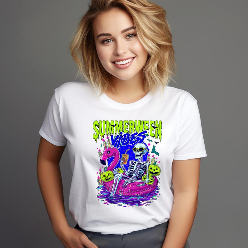 以下が含まれることがあります： カラフルなグラフィックが施された白いTシャツ。ピンクのフラミンゴの浮き輪に乗った骸骨、ハロウィンのカボチャ、緑と青で「SUMMERWEEN VIBES」の文字が描かれています。Tシャツはクルーネックです。