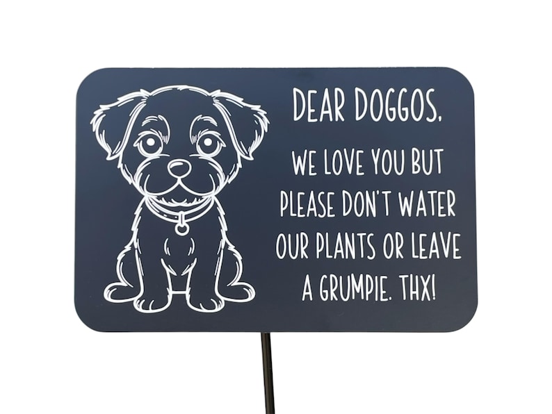Black aluminum sign with an engraved cartoon dog and humorous message: 'Dear Doggos, we love you but please don't water our plants or leave a grumpie. Thx!' Designed for pet-friendly gardens and respectful dog walking.