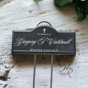 Puede incluir: Una placa conmemorativa grabada en blanco y negro con una cruz plateada y el texto "En memoria de Gregory T. Caldwell MISTER LINCOLN".