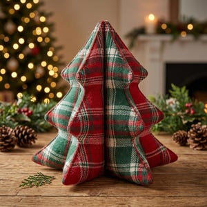 May include: A three-dimensional fabric Christmas tree decoration featuring a red, green, and white plaid pattern. The soft, stuffed ornament has a multi-tiered, pointed shape and is constructed from woven textile material with visible seams.