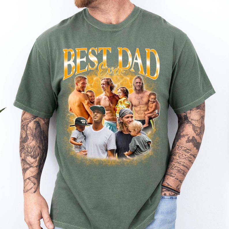 May include: An olive green short-sleeve t-shirt featuring a graphic print with the text "BEST DAD Ever" in yellow. The design includes a collage of multiple photographs showing various fathers and children in a warm, golden-toned background.