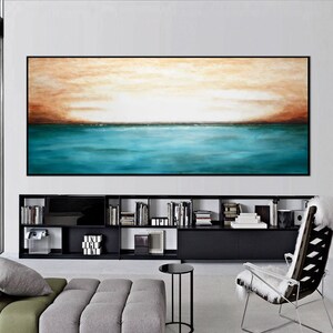 May include: Abstract painting of a seascape with a teal blue ocean and a brown and orange sky. The painting is hanging on a wall above a black bookshelf.