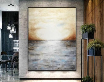 May include: Large abstract painting with a black frame. The artwork features a gradient of colors, with a light beige upper section transitioning to a brown band, and a gray and blue lower section. The painting is displayed in a modern interior.