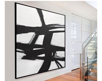 May include: Abstract black and white painting with bold brushstrokes on a white canvas. The painting is framed in a black frame and is hanging on a white wall.