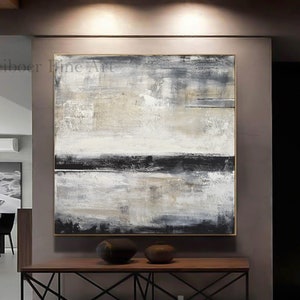 May include: Abstract landscape painting with a gold frame. The artwork features a textured surface with a palette of white, gray, and black. The painting is displayed above a wooden console table with two decorative vases.