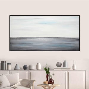 May include: Abstract painting of a seascape with a white sky and a gray and blue ocean. The painting is framed in black.