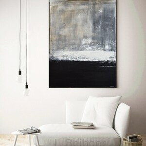 May include: Abstract painting with a white, gray, and black color scheme. The painting is hanging on a white wall above a white couch.
