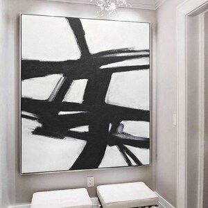 May include: Abstract black and white painting with bold brushstrokes on a white canvas. The painting features a series of intersecting lines and shapes, creating a dynamic and modern composition.