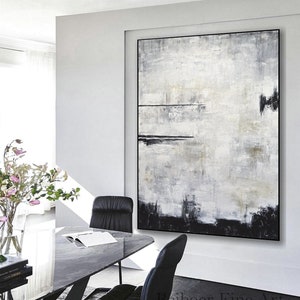 Op de afbeelding: Groot abstract schilderij met zwarte lijst. Het kunstwerk toont een textuurontwerp in tinten wit, grijs en zwart. Het heeft een horizontale zwarte lijn en een zwarte basis. De stijl is modern en minimalistisch, geschikt voor moderne interieurs.
