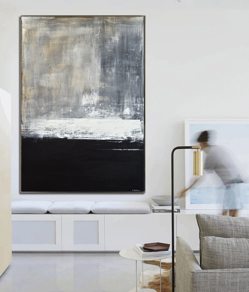 May include: Abstract painting with a black, white, and gray color scheme. The painting is hung on a white wall in a modern living room.