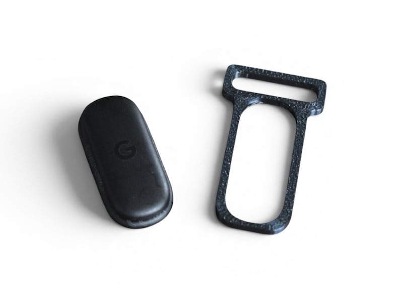 May include: Two black objects on a white background. One is a rounded rectangle with a debossed "G" logo. The other is a dark gray, textured, rectangular frame with a large opening.