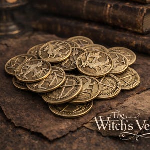 Può includere: Una collezione di monete antiche color oro con vari disegni in rilievo, tra cui draghi e altri simboli, è ammucchiata su una superficie marrone strutturata. Il logo The Witch's Vessel è visibile in basso a destra.