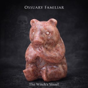 Könnte beinhalten: Rotbraune Bärenfigur mit dem Text "Ossuary Familiar" und "The Witch's Vessel". Der Bär sitzt mit verschränkten Pfoten. Der Hintergrund ist dunkel mit einer Totenkopf-Silhouette.