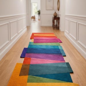 May include: A hallway featuring a series of rectangular rugs in a vibrant colour palette. The rugs display a gradient of colours, including orange, red, pink, purple, blue, green, and yellow. The rugs are placed on a light-coloured wooden floor.