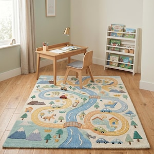 May include: A colorful children's rug with a road and river design. The rug features a winding yellow road, a blue river, and illustrations of cars, houses, and trees. The rug is placed under a wooden desk and chair.