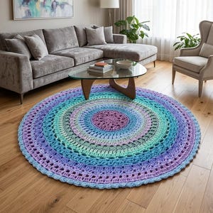 Op de afbeelding: Een groot, rond, met de hand gehaakt kleed met een levendig kleurverloop. Het ontwerp bestaat uit concentrische ringen die verlopen van een dieppaars midden naar tinten lichtblauw, groenblauw en groen, eindigend in een geschulpte rand.