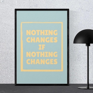 May include: A framed poster with the text "NOTHING CHANGES IF NOTHING CHANGES" in yellow on a light blue background. A black desk lamp with a rounded shade is to the right of the poster.