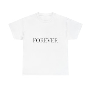 Peut inclure: T-shirt blanc avec le mot "FOREVER" imprimé en noir, centré sur le devant. Le t-shirt a un col rond et des manches courtes. Le tissu semble être un matériau doux et léger.