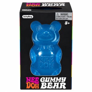May include: A blue translucent gummy bear-shaped toy inside a black rectangular box. The packaging features the text Nee Doh Gummy Bear, the Schylling logo, and a choking hazard warning. The bear has a molded face with swirl eyes and a bow tie.
