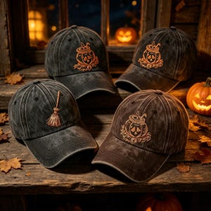 Puede incluir: Cuatro gorras de béisbol de tela gris carbón desgastada. Tres gorras presentan un gráfico bordado en naranja de una calabaza con una vela dentro, mientras que una gorra muestra un gráfico bordado en naranja de una escoba.
