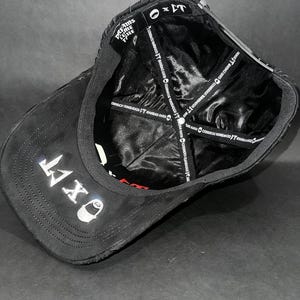 May include: Black baseball cap with the text "OXT" embroidered in white on the front. The cap features a curved brim and a satin lining. The text "DREAMS COME TRUE" is visible on the side.