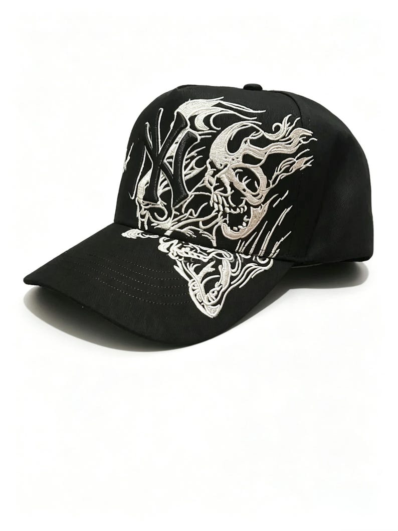 May include: Black baseball cap with a curved brim. The cap features a white embroidered design of a skull and flames, along with the letters "NY". The cap is made of a durable fabric and has a structured fit.
