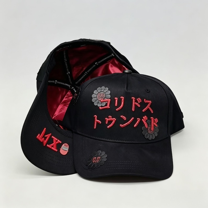 May include: Black baseball cap with red Japanese text and floral accents. The cap's interior is lined with red satin. The brim features red text and a small graphic. A stylish accessory for casual wear.