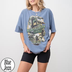 K&ouml;nnte beinhalten: Hellblaues kurz&auml;rmeliges T-Shirt mit einem Grafikdesign aus der Star Wars-Serie "The Mandalorian and Grogu". Der Aufdruck enth&auml;lt den Text "THIS IS THE WAY".