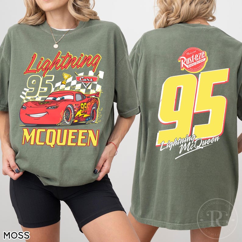 May include: Moss green t-shirt featuring Lightning McQueen from the Cars movie. The front graphic includes the number 95, a checkered flag, and the text "Lightning McQueen" and "MCQUEEN". The back displays a large yellow number 95 and the text "Lightning McQueen".