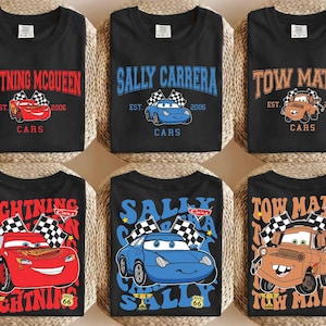 以下が含まれることがあります： 映画「カーズ」のキャラクターが描かれた黒いTシャツ6枚。デザインには、ライトニング・マックィーン、サリー・カレラ、メーターなどが、テキストとグラフィックで描かれています。各シャツは異なるデザインで、カーズのロゴと2006年が描かれています。