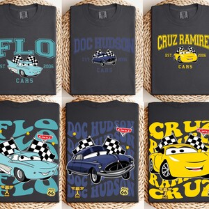 以下が含まれることがあります： 車をテーマにしたグラフィックが施された、濃いグレーのTシャツ6枚。デザインには「FLO」、「DOC HUDSON」、「CRUZ RAMIREZ」の名前が使われており、それぞれに漫画の車と「CARS」の文字が添えられています。シャツには「2006」の年も表示されています。